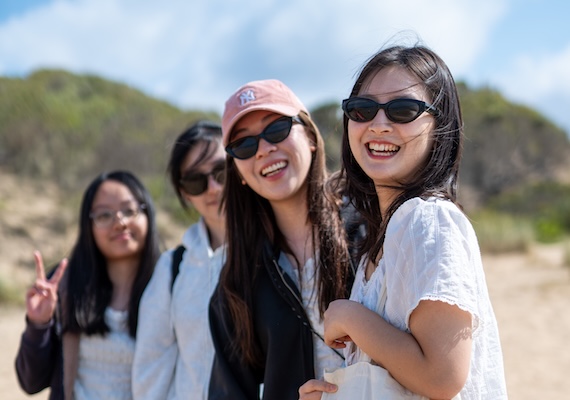 Four study abroad students smiling on the beach in Australia.