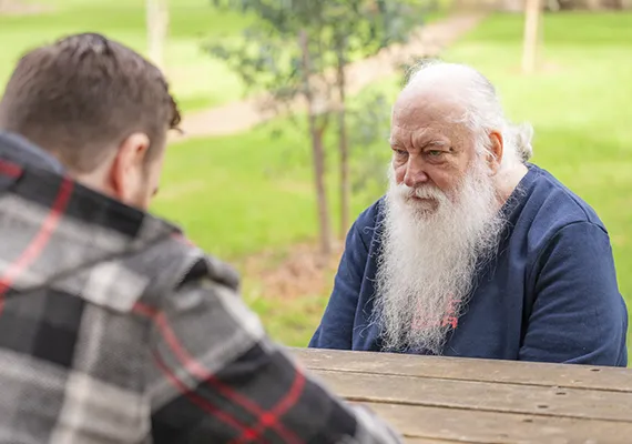 Bryan Fricker facing Al Fricker on picnic table