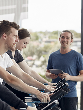 Deakin students on exercise bikes woking on sports performance with a coach at Deakin University Elite Sports Precinct.