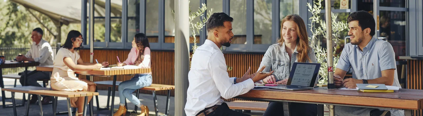 Three Deakin students working together at a table near a window