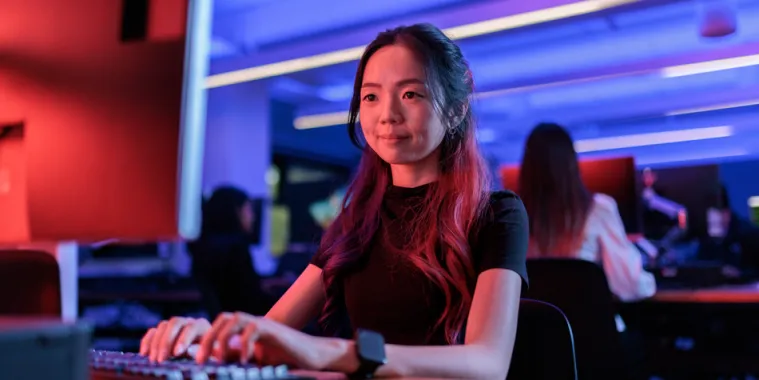 A student sits at a computer with her hands resting on the keyboard