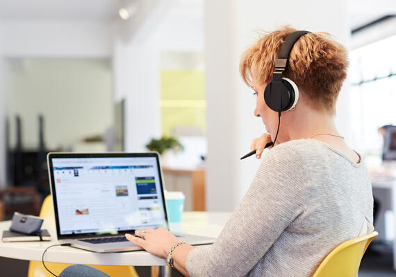 Side profile of student on a laptop with headphones