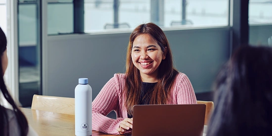 Student facing two other students talking across table