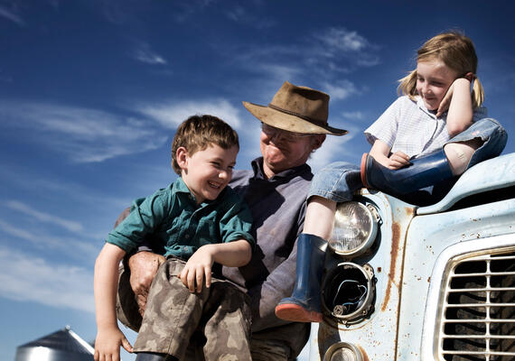 a farmer stands next to a truck with two young children