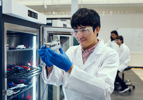 A researcher wearing gloves and working in a materials lab.