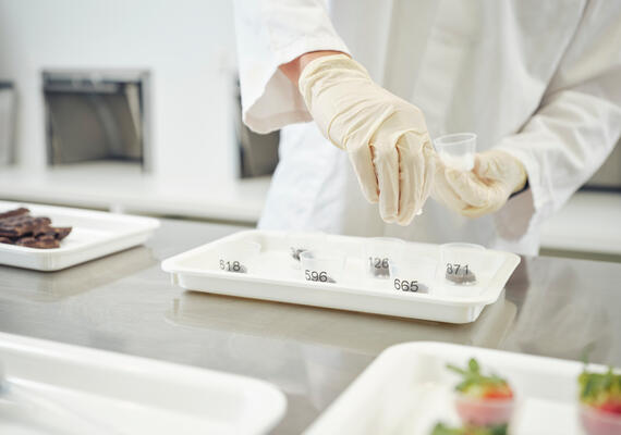 Gloved hand placing food samples into plastic cups