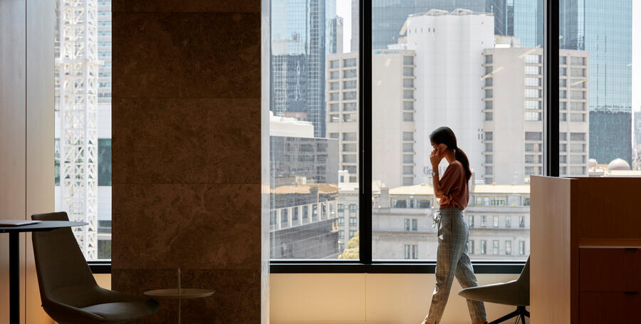 A Deakin University professional talking on the phone silhouetted by a window at Melbourne Downtown Corporate Centre.
