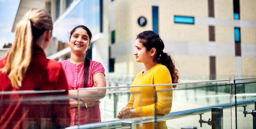 Three students standing near a cafe on Deakin campus