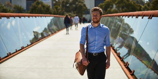 Student walking across bridge with glass sides