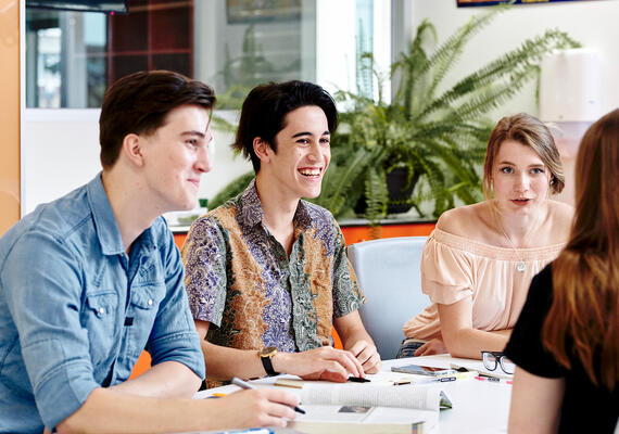 Deakin students sitting around table talking and smiling.