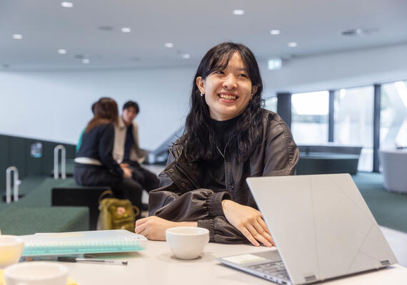 International student with a laptop, sitting at a table on Burwood campus