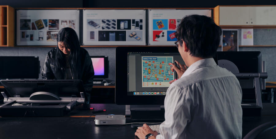 Two Deakin students working on design projects in a computer lab.