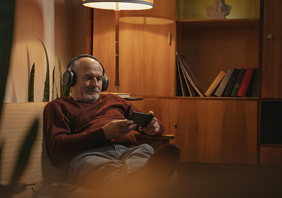A person sitting in their living room at nighttime, choosing an audiotrack
