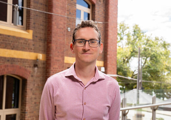 Deakin lecturer Diarmaid Harkin standing in front of a building on the Geelong Waterfront Campus.