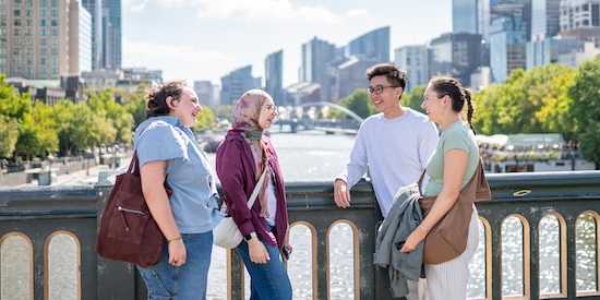 A group of study abroad and exchange students standing and talking on a bridge in the middle of Melbourne.