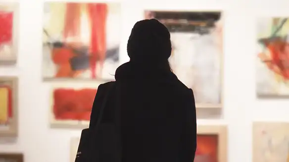 A visual arts student is at the gallery in front of an artwork.