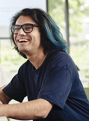 Deakin student laughing while sitting at a table on the Melbourne Burwood Campus.