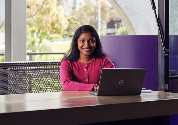 A Deakin international student sits at a cafe with a laptop