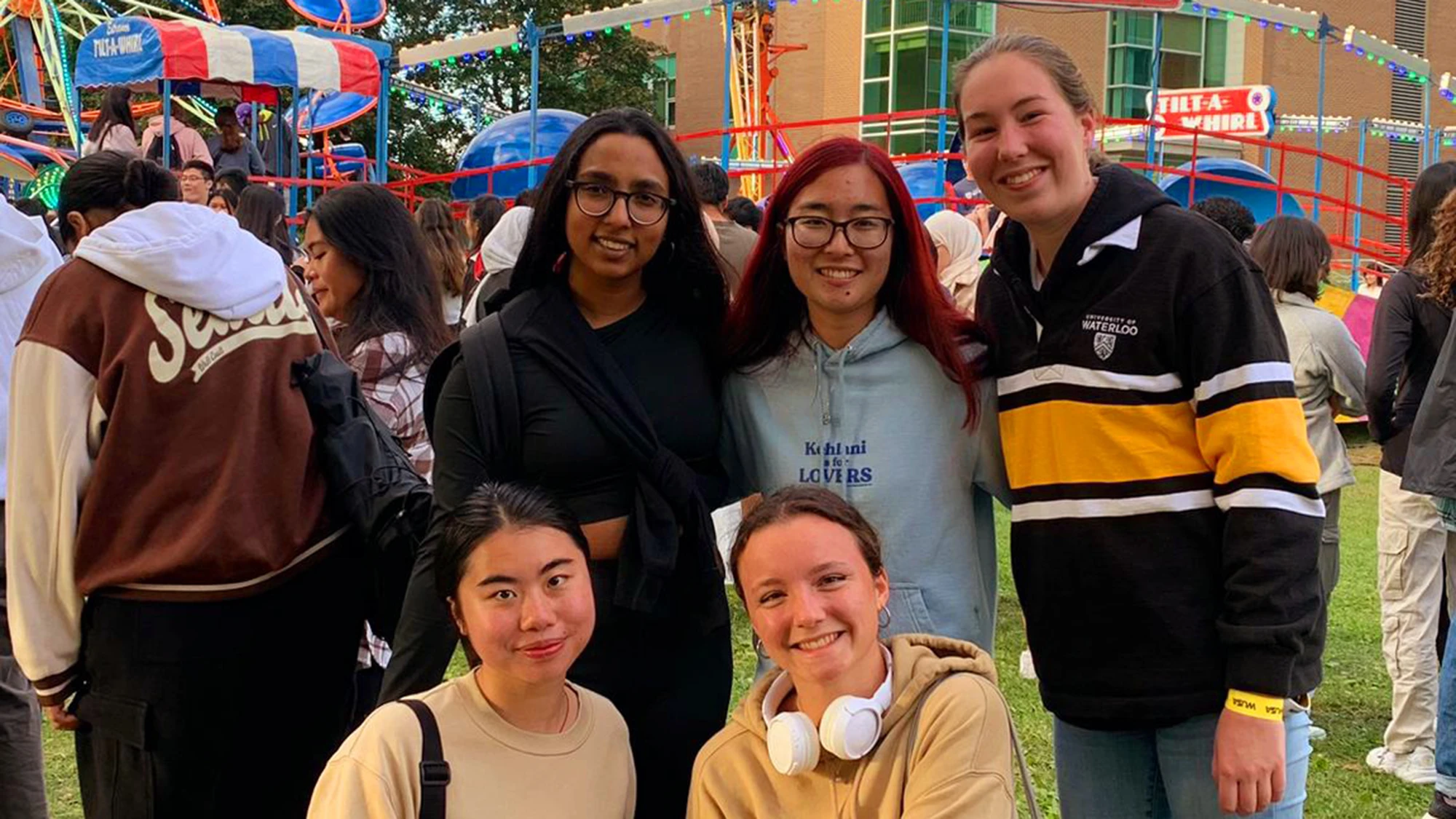 Kaviya and four friends smile at the camera. A fair is in the background, including a Tilt-A-Whirl ride.