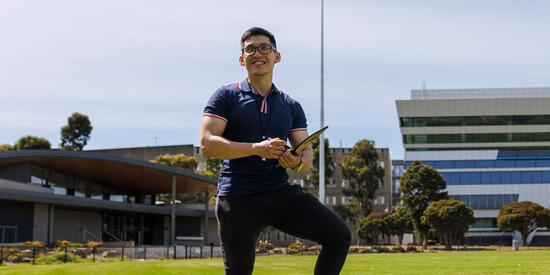 Student on oval with clipboard.