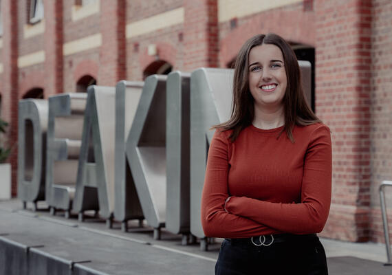 Bachelor of Psychological Science student Emily Brown standing in front of a Deakin sign.