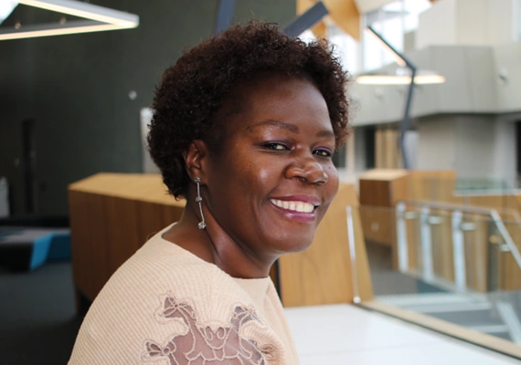 Master of Education student Felizarda of Mozambique turned to one side, smiling at the camera on campus.