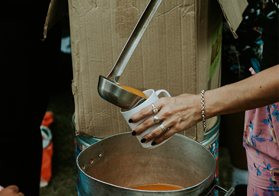 A volunteer pouring soup into a mug.