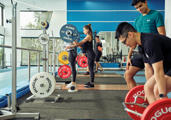 Deakin sport science student lifting weights at Burwood Campus.
