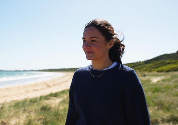 Pearl Mitchell standing near a beach, staring at the ocean