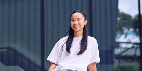 Student sitting outdoors on campus smiling