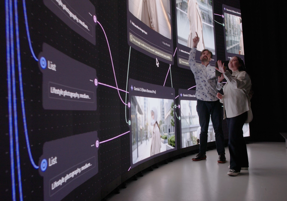 Two Deakin Master of AI for Design and Creative Practice professors pointing at a screen on stage.