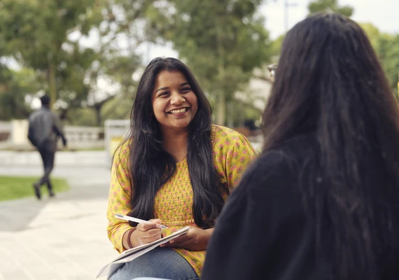 A Deakin undergraduate student smiles while soicalising on campus