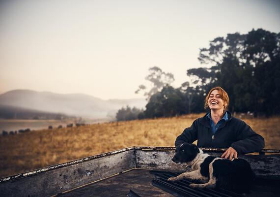 a person stands by a ute with a dog 