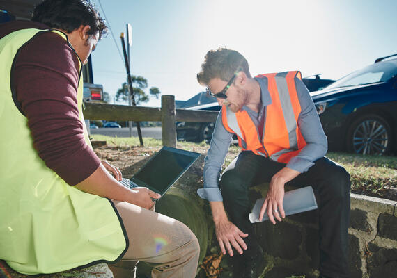 Two people work at a water monitoring station.