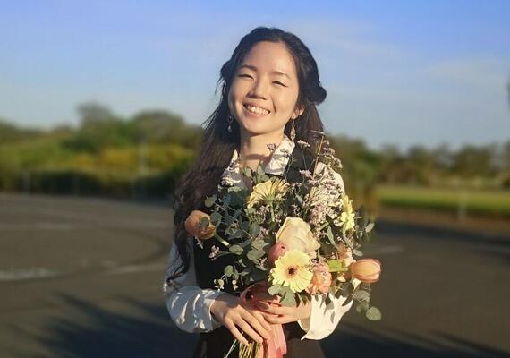 Deakin bachelor of cyber security student derby teo smiling with bouqet of flowers.