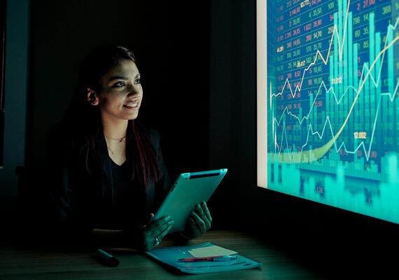 Business Analytics student with ipad looking at a graph on a screen