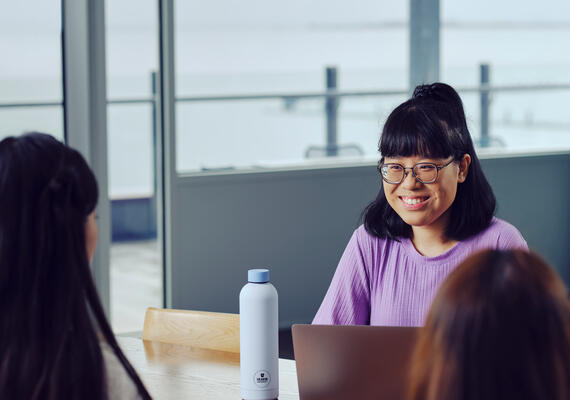 A student sitting at a table with an open laptop at the Geelong Waterfront Campus.