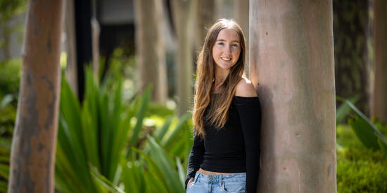 Deakin Young Influencer Award recipient Ella Gray standing outside against a tree smiling.