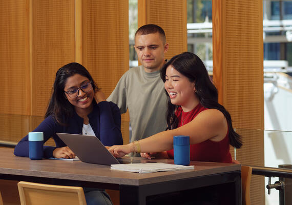 Three Deakin Guaranteed ATAR students sit at a desk with a laptop.