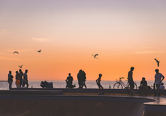 A landscape image of silhouetted people at a beach at sunset