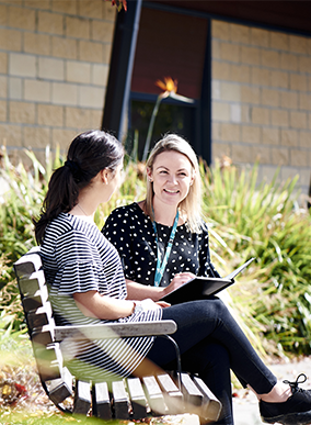 Two students talking on a bench