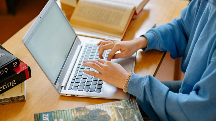 Image of a student typing on a laptop at a desk