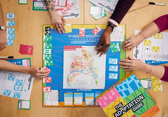 Several hands over a board game, playing the interactive TAG game.