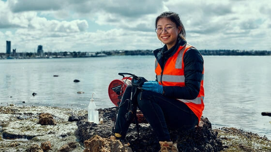 A Deakin engineering student with a tool near the ocean.