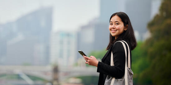 Student with phone outdoors.