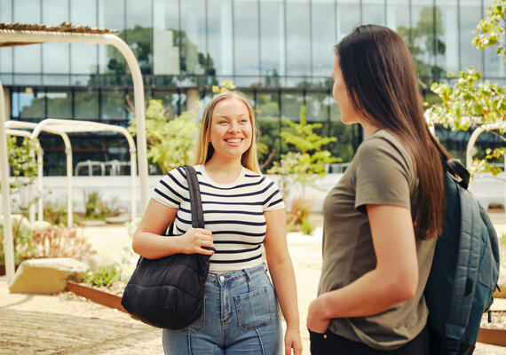 Two Deakin students talking and smiling on campus.