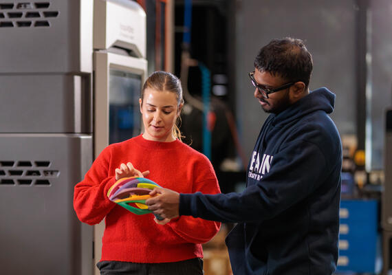 Two Deakin bachelor of exercise and sport science students look at a bike helmet prototype