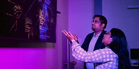A student and lecturer looking at a large computer screen