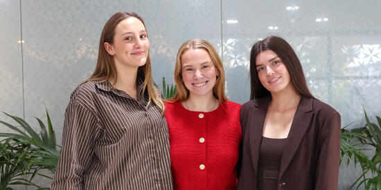 Two Deakin Public Health placement students standing with their Deakin Alumni placement supervisor.