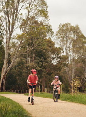 Two children ride bikes outside.